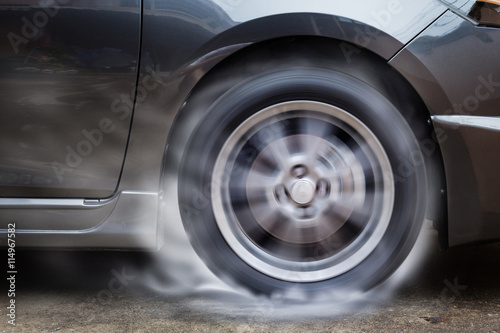 Car racing spinning wheel burns rubber on floor. © jayzynism