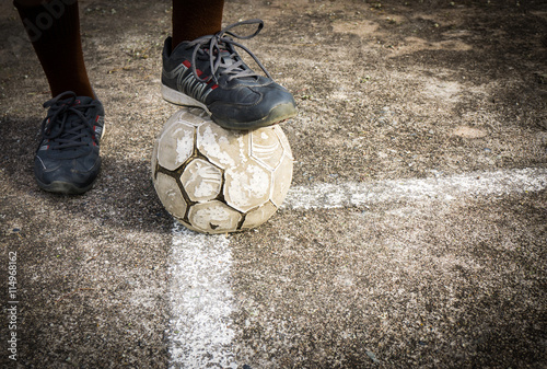 Old soccer ball on concrete field with soccer boots