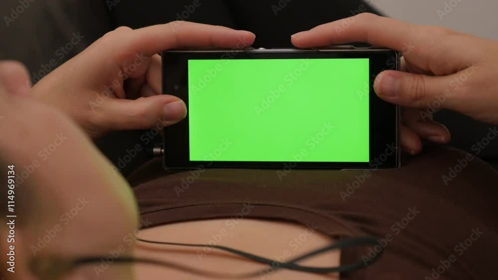Chroma green screen on phone while female listening the music 4K 2160p UHD footage - Woman listening music on snart phone headphones 4K 3840X2160 UHD video