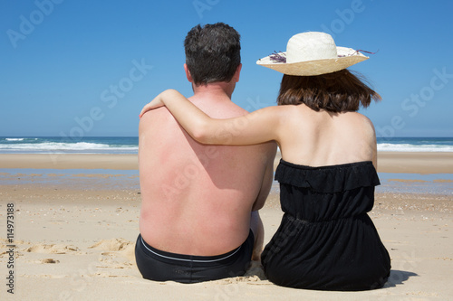 Back view of romantic couple enjoying sunny day at beach photo