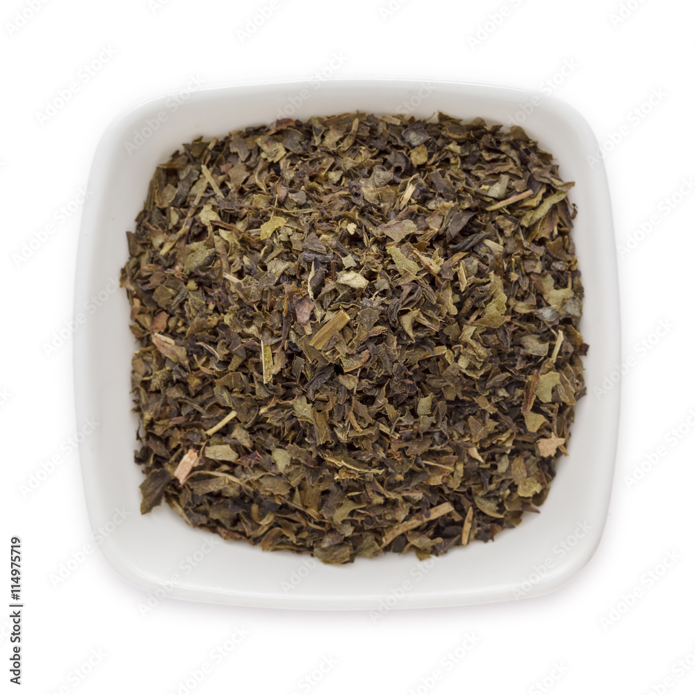 Organic Green tea (Camellia sinensis) Tea bag cut, dried leaves, in white ceramic bowl isolated on white background. Macro close up. Top view. Organic Green tea (Camellia sinensis) Tea bag cut, dried leaves, in white ceramic bowl isolated on white background. Macro close up. Top view.