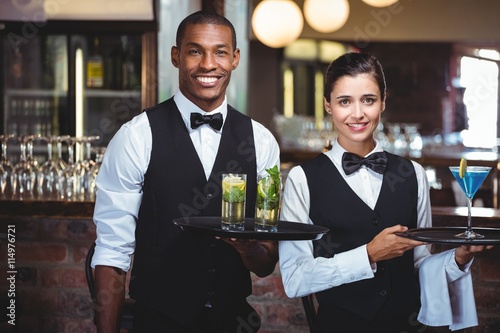 Mixed race waiter and waitress holding a serving tray photo