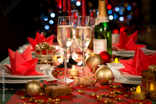 Fototapeta christmas eve party table with champagne flute with red and golden glitter