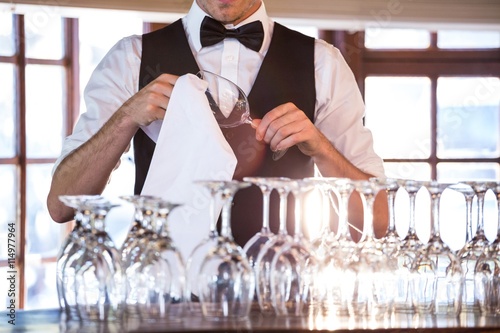 Mid section of bartender cleaning wineglass 