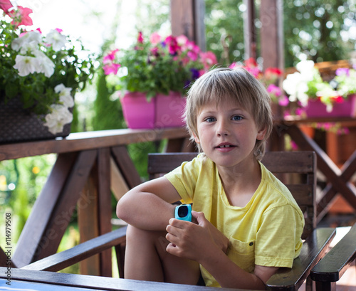 Cute boy using smart watch  on a terrace  