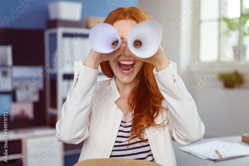 lachende geschäftsfrau schaut durch papierrollen
