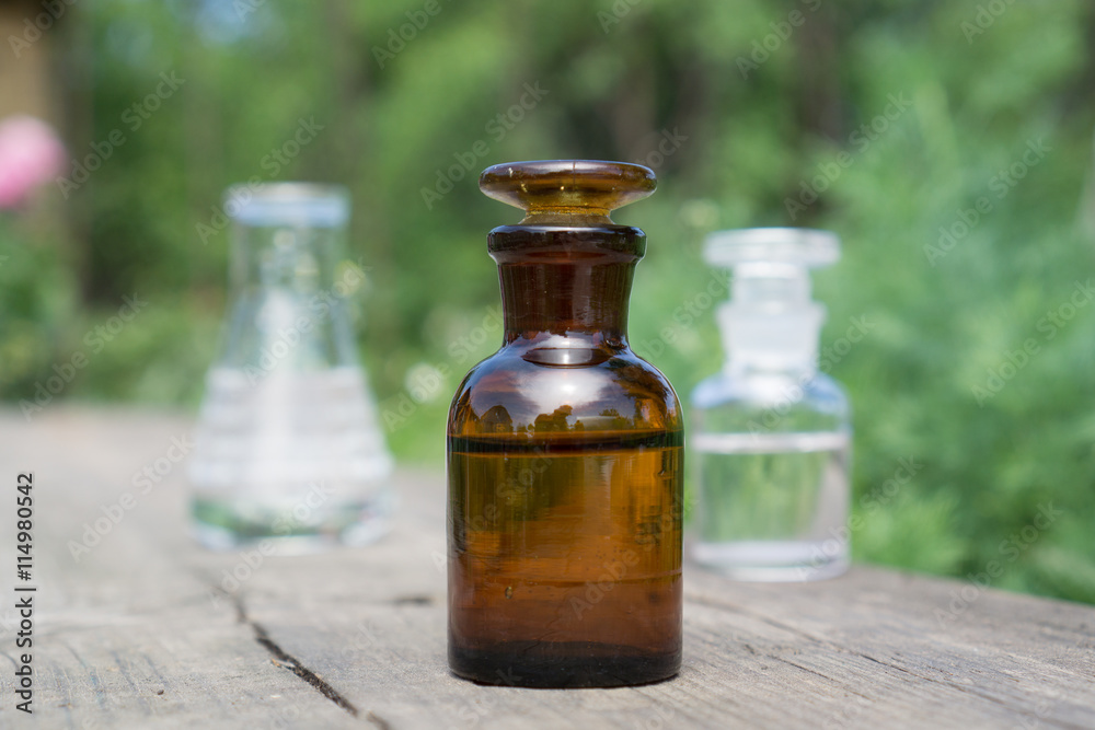 Liquid in chemical ware on a background of plants, fertilizers or pesticides in the garden. Liquid in chemical ware on a background of plants, fertilizers or pesticides in the garden.