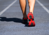 Runner feet running on road closeup on shoe. Woman fitness jog w