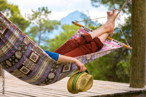 Obraz na plátně Person relaxing in Hummock holding Travel Hat