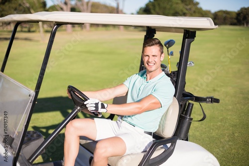 Happy golfer man driving golf buggy