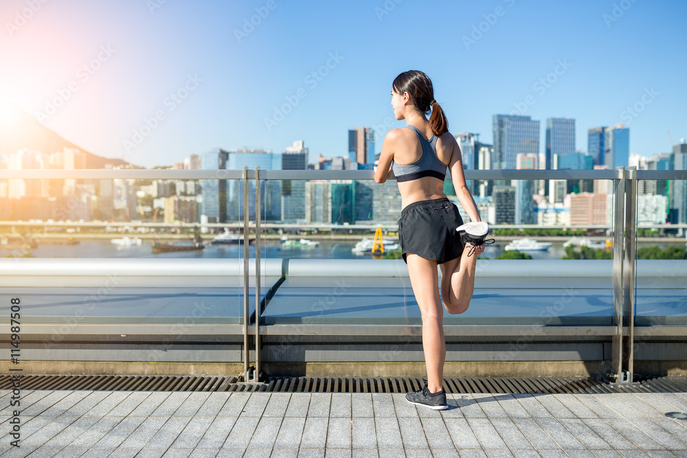 The back view of woman stretching legs in city
