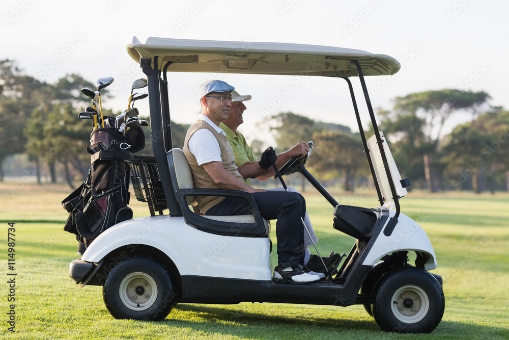 Golfer friends sitting in golf buggy