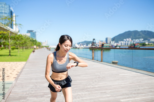 Woman using wearable watch when running outside © leungchopan