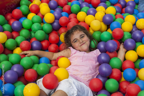 Girl lie down in a colorful plastic ball pool