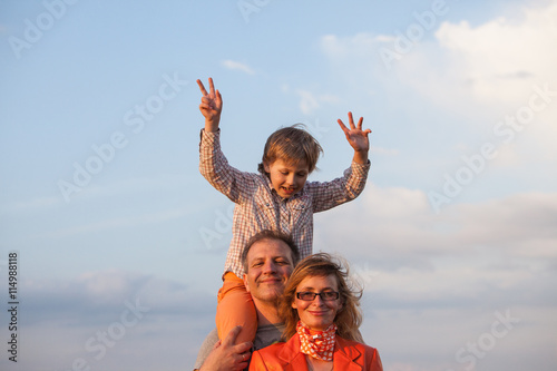 Happy family: mother, father and son. Boy sitting on his father's neck 