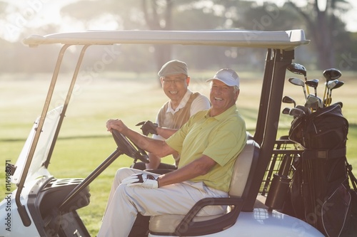 Portrait of cheerful golfer friends sitting in golf buggy 