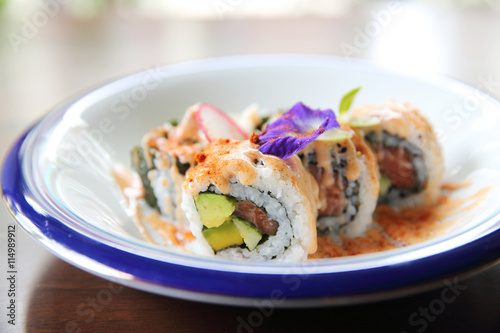 salmon tuna and avocado uramaki with spicy sauce in close up