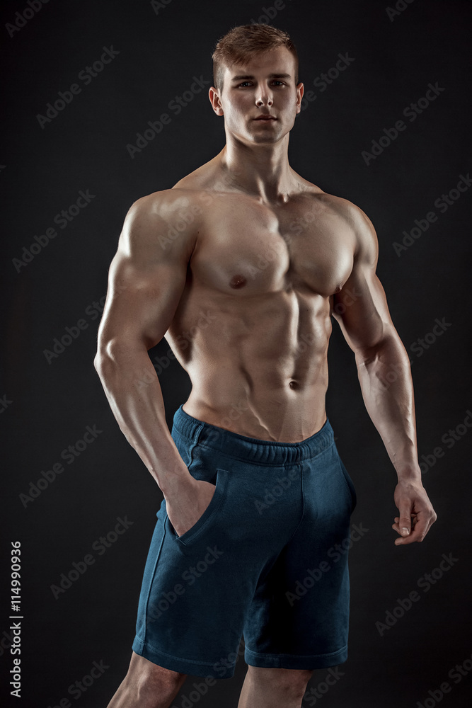 Muscular bodybuilder guy doing posing over black background