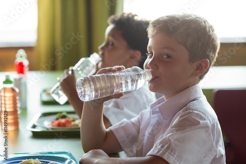 Portrait of schoolboy drinking water from bottle