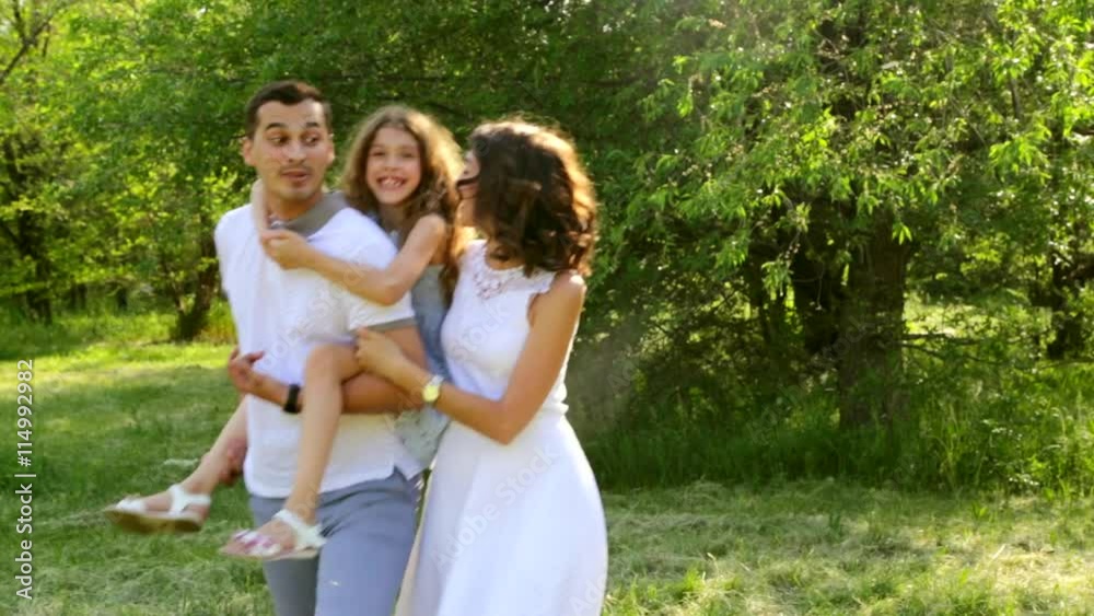 Happy family walking in a park daughter sitting on her father shoulders full HD Happy family walking in a park daughter sitting on her father shoulders full HD
