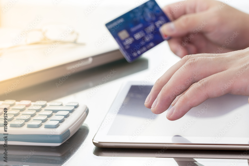 Man using his digital tablet while holding a credit card intent to online shopping, concept with digital business or e-commerce concept. close up, warm tone. Man using his digital tablet while holding a credit card intent to online shopping, concept with digital business or e-commerce concept. close up, warm tone.