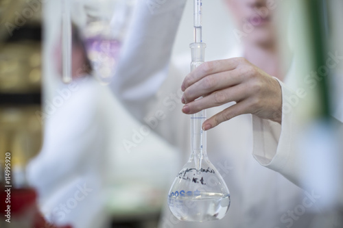 Scientist in lab holding round-bottom flask photo