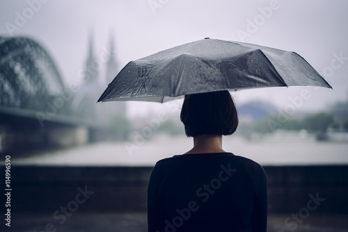 Germany, Cologne, back view of woman with umbrella on a rainy day photo