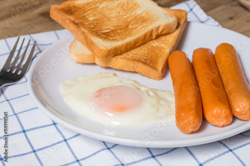 breakfast with fried eggs,sausage and toasts on wooden table