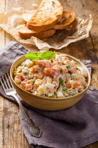 Wooden bowl of traditional russian salad on wooden table