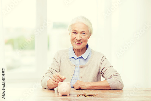 senior woman putting money to piggy bank at home
