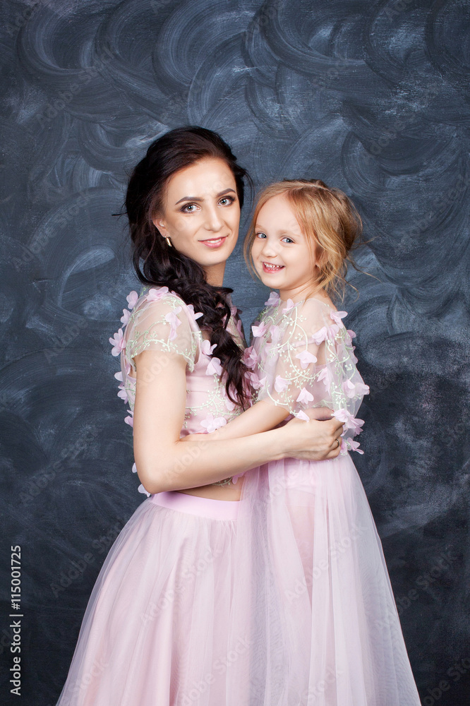 Portrait of mother and daughter in identical dresses. Familylook Portrait of mother and daughter in identical dresses. Familylook