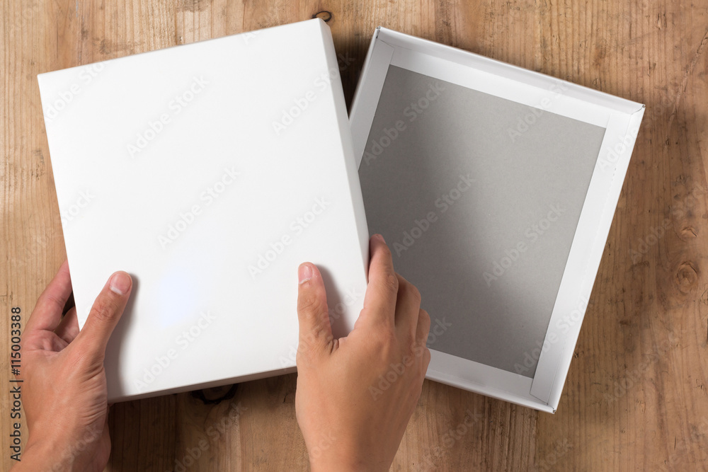 Hand opened cardboard box on wooden background Hand opened cardboard box on wooden background