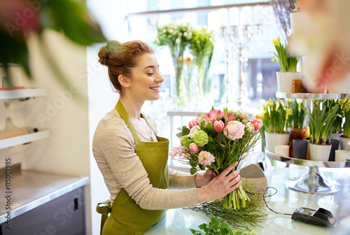 smiling florist woman making bunch at flower shop photo