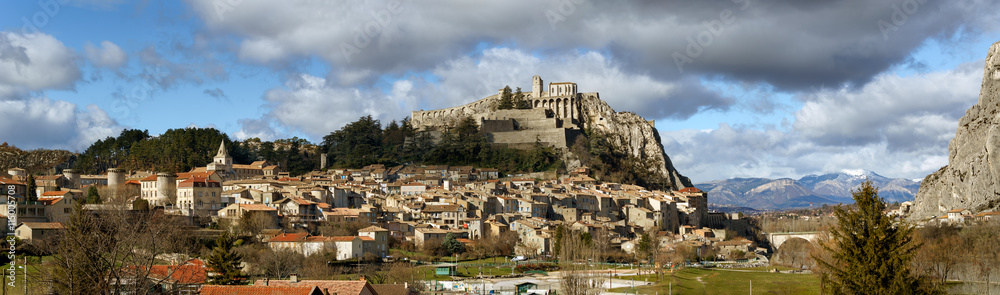 Panoramic view of Sisteron rooftops and the Citadel in summer light with clouds. The Sisteron Citadel and its fortifications is located in the Southern Alps (Alpes de Haute Provence), France Panoramic view of Sisteron rooftops and the Citadel in summer light with clouds. The Sisteron Citadel and its fortifications is located in the Southern Alps (Alpes de Haute Provence), France