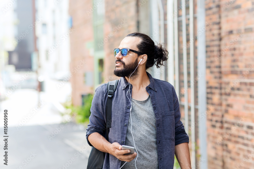 man with earphones and smartphone walking in city