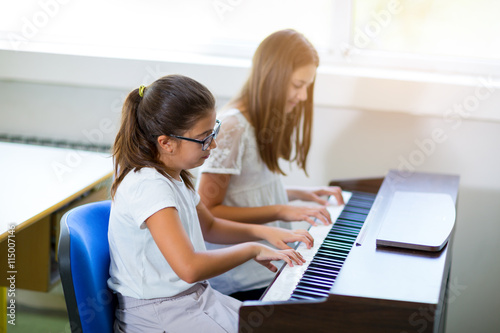 Two girls playing the piano at the music school, selective focus