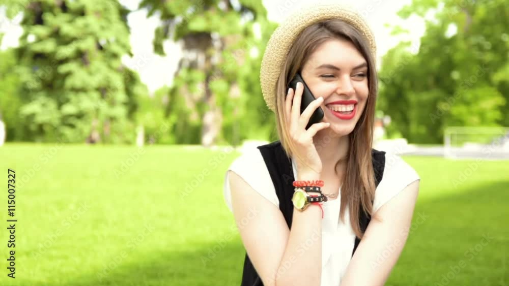 Cute young woman speaking on a mobile phone on the grass Cute young woman speaking on a mobile phone on the grass