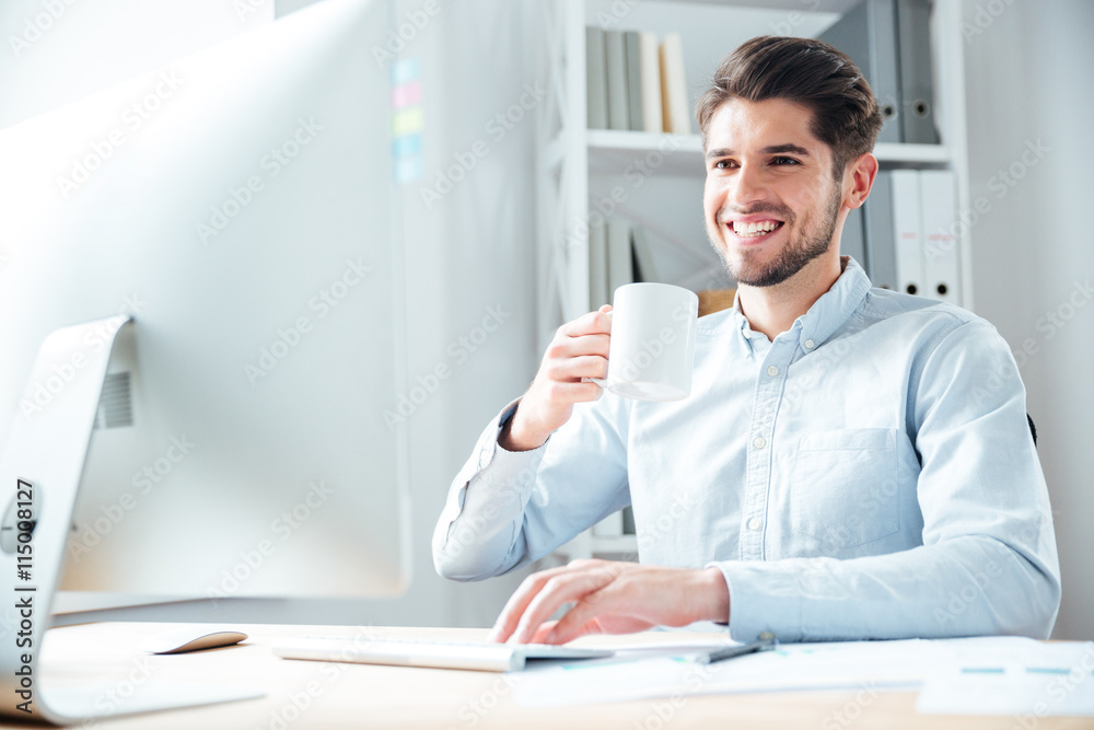 Fototapeta premium Young businessman in casual cloth drinking coffee in office