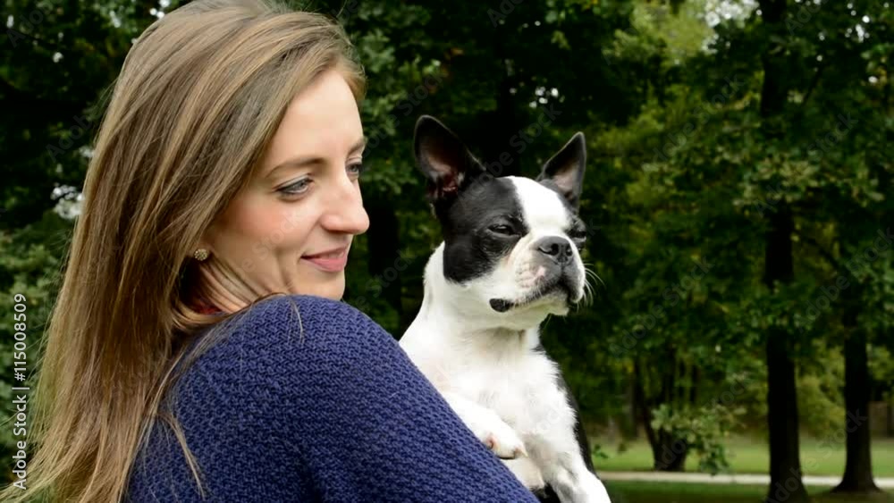 young attractive woman carries french bulldog in the park - she observes behavior of dog - close up young attractive woman carries french bulldog in the park - she observes behavior of dog - close up