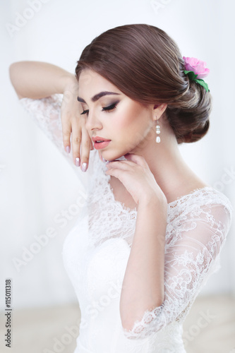 Portrait of a beautiful brunette bride bright makeup and hairstyle in lace dress