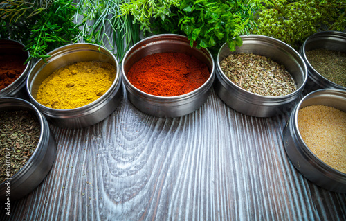 Fototapeta Naklejka Na Ścianę i Meble -  Spices in metal containers and fresh herbs on wooden table