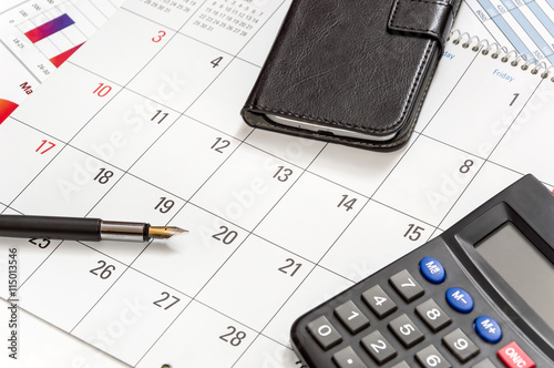 Pen, calculator and smartphone on the calendar photo