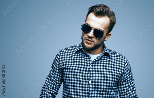 Handsome stylish young man. Brutal man with a beard and sunglasses. Looking at the camera © Cressida studio