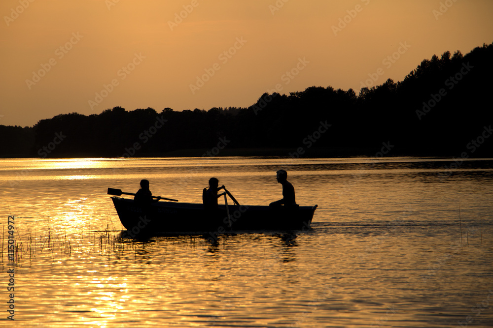 rowing wooden boat near forest in late evening during sunset