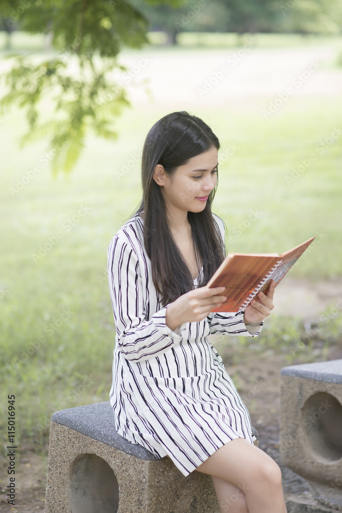 Fototapeta premium Attractive woman reading a book in the park