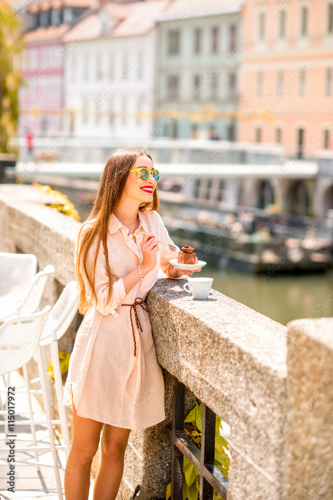 Young woman enjoying traditional slovenian chocolate cake near the river in the center of Ljubljana city. Traveling Slovenia