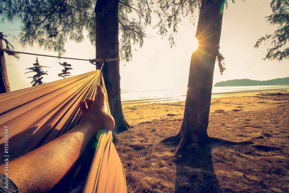 Fototapeta premium man feet sleeping on swing at the sunset beach background.