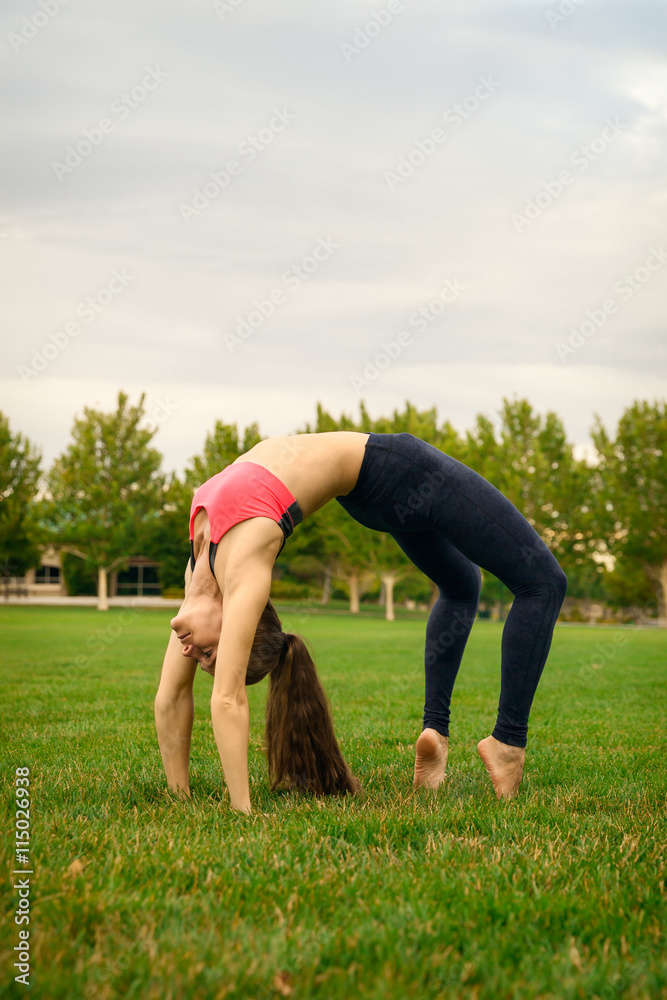 Fototapeta premium Pretty woman doing yoga exercises in the park