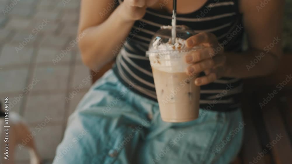 Woman drinking cold coffee with ice, whipped cream and caramel syrup with a straw. closeup Woman drinking cold coffee with ice, whipped cream and caramel syrup with a straw. closeup