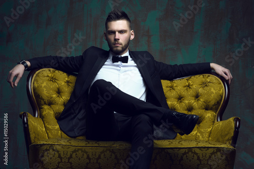 Stylish young man in a suit and bow tie. Business style. Fashionable image. Evening dress. Sexy man standing and looking at the camera. Fashion look